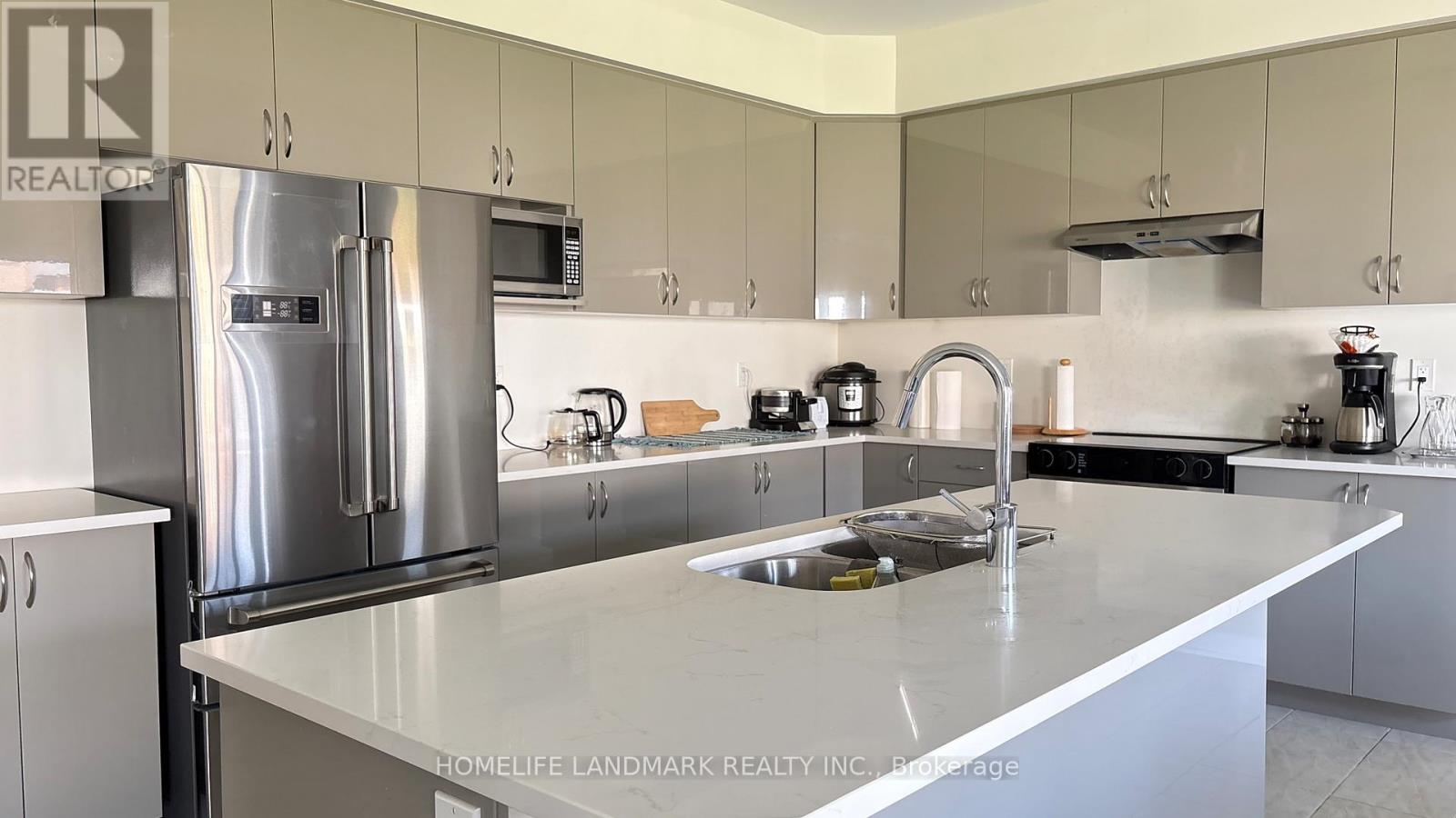 A modern kitchen with a stainless steel refrigerator and a white countertop.