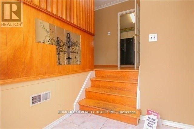 A hallway with a wooden staircase and a sign on the floor.