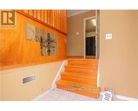 A hallway with a wooden staircase and a sign on the floor.