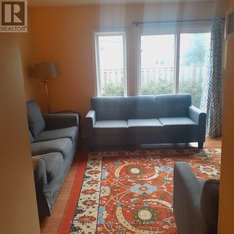 A living room with a grey couch, a grey chair, and a red patterned rug.