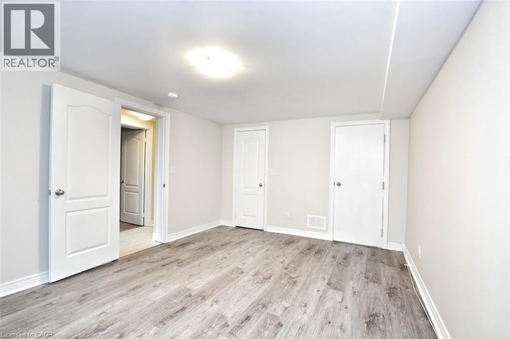 A spacious room with white walls and wooden flooring, featuring a doorway leading to another room.