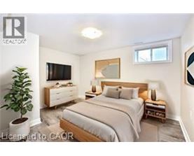 A bedroom with a bed, nightstand, and a plant.