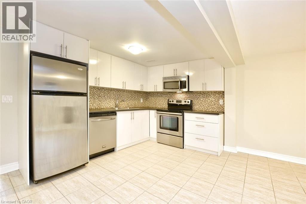 A kitchen with a refrigerator, microwave, oven, and sink.