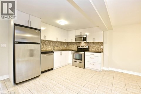 A kitchen with a refrigerator, microwave, oven, and sink.