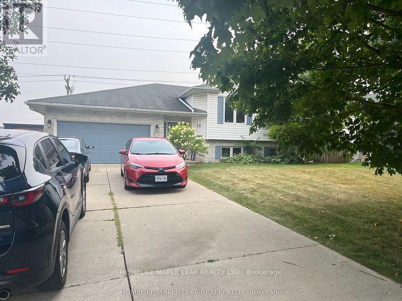 Two cars parked in front of a house with a sign that says "HomeLife Maple Leaf Realty LTD Brokerage".