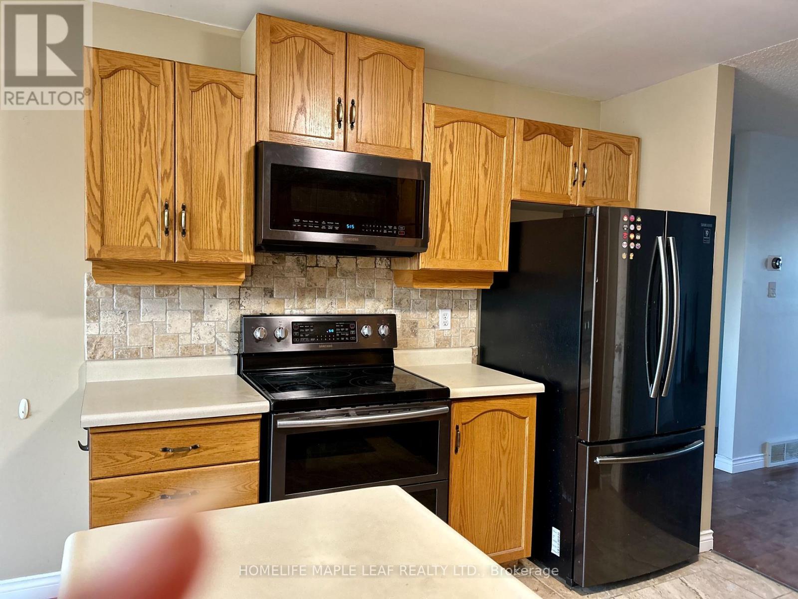 A kitchen with wooden cabinets and a black refrigerator.