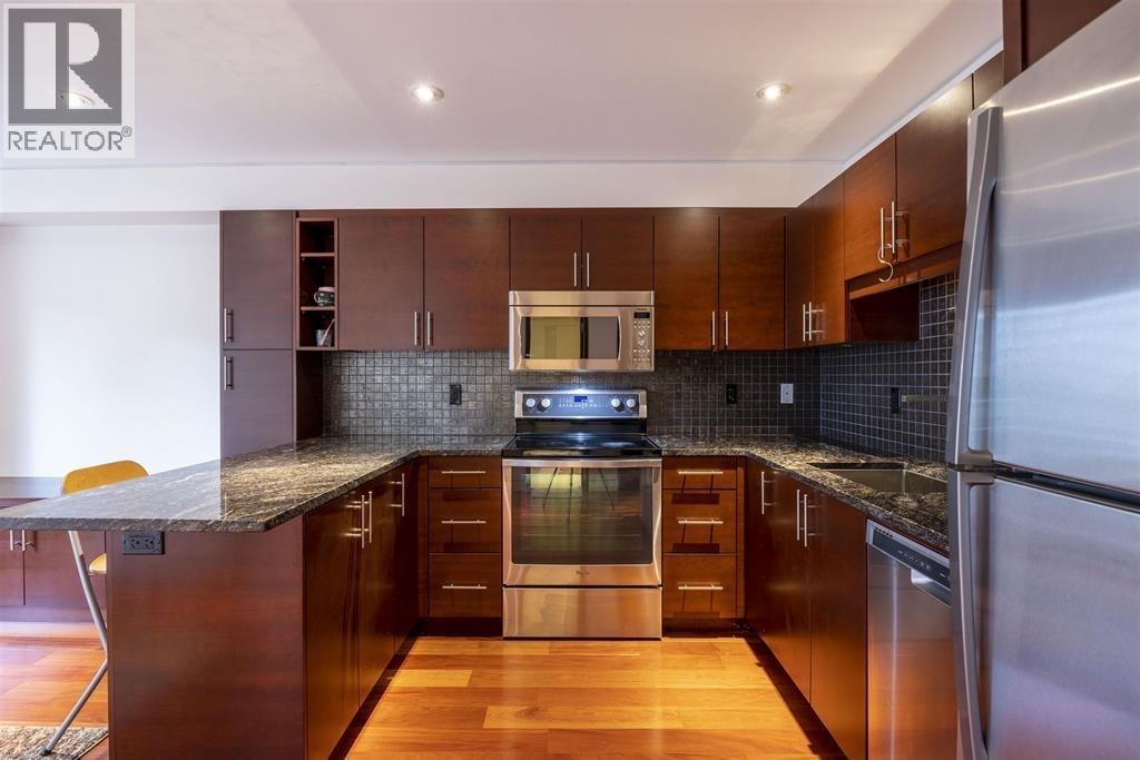 A modern kitchen with dark wood cabinets and stainless steel appliances.