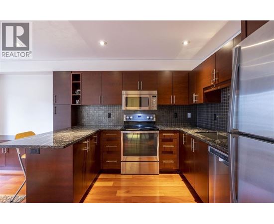 A modern kitchen with dark wood cabinets and stainless steel appliances.