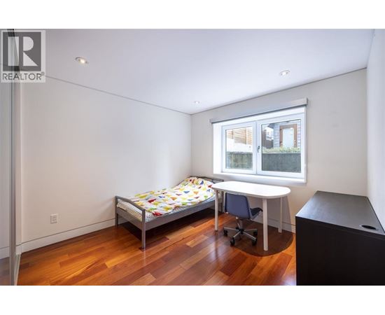 A bedroom with a bed, desk, and chair.