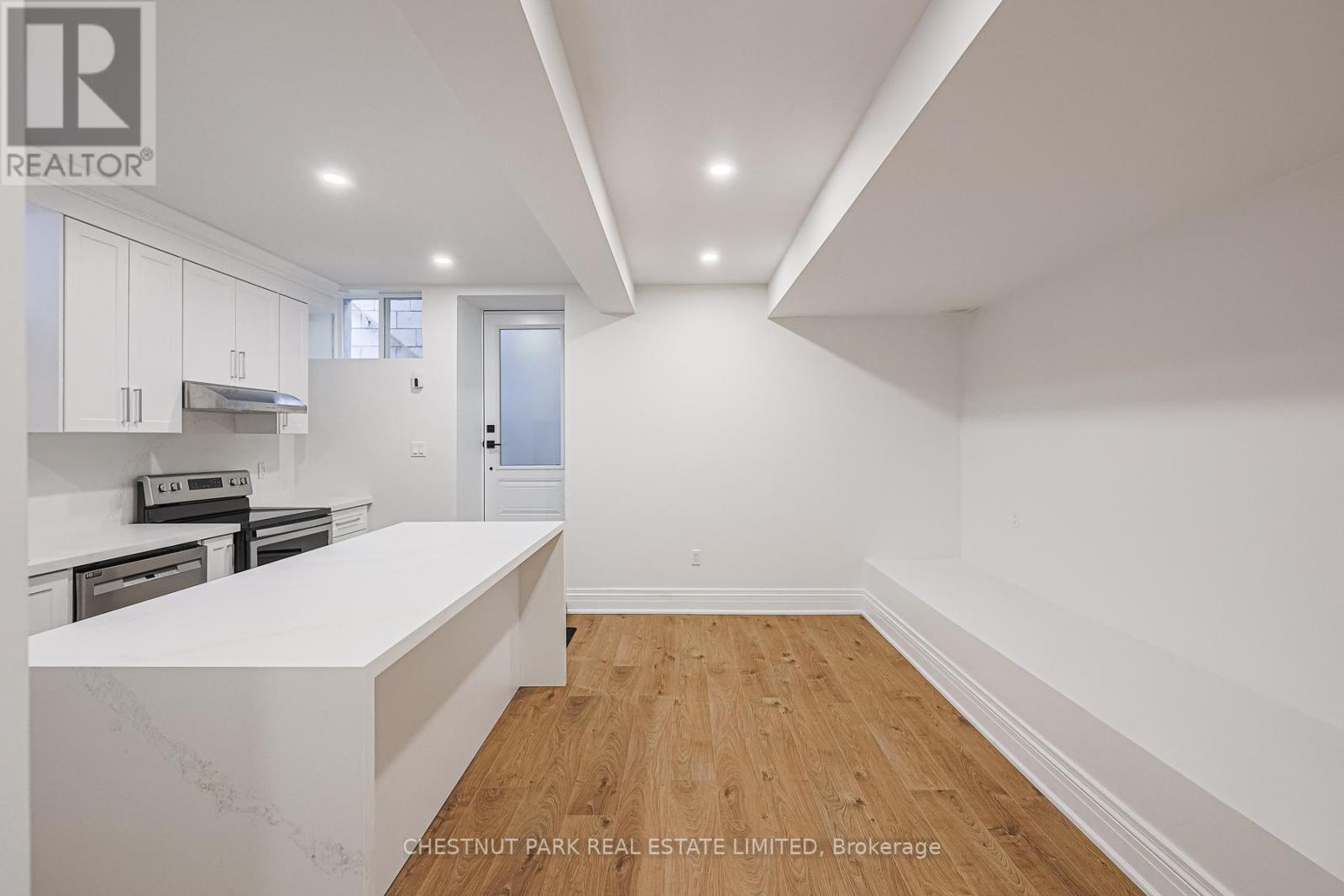 A white kitchen with wooden floors and a white counter top.