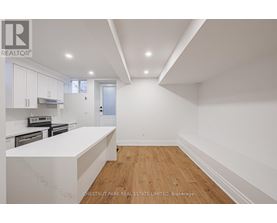 A white kitchen with wooden floors and a white counter top.