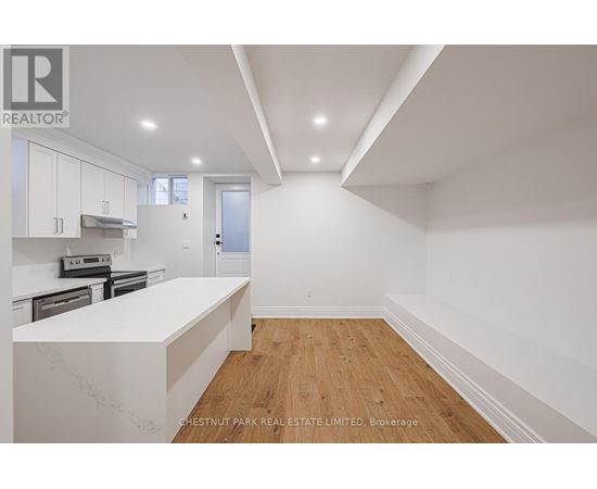 A white kitchen with wooden floors and a white counter top.