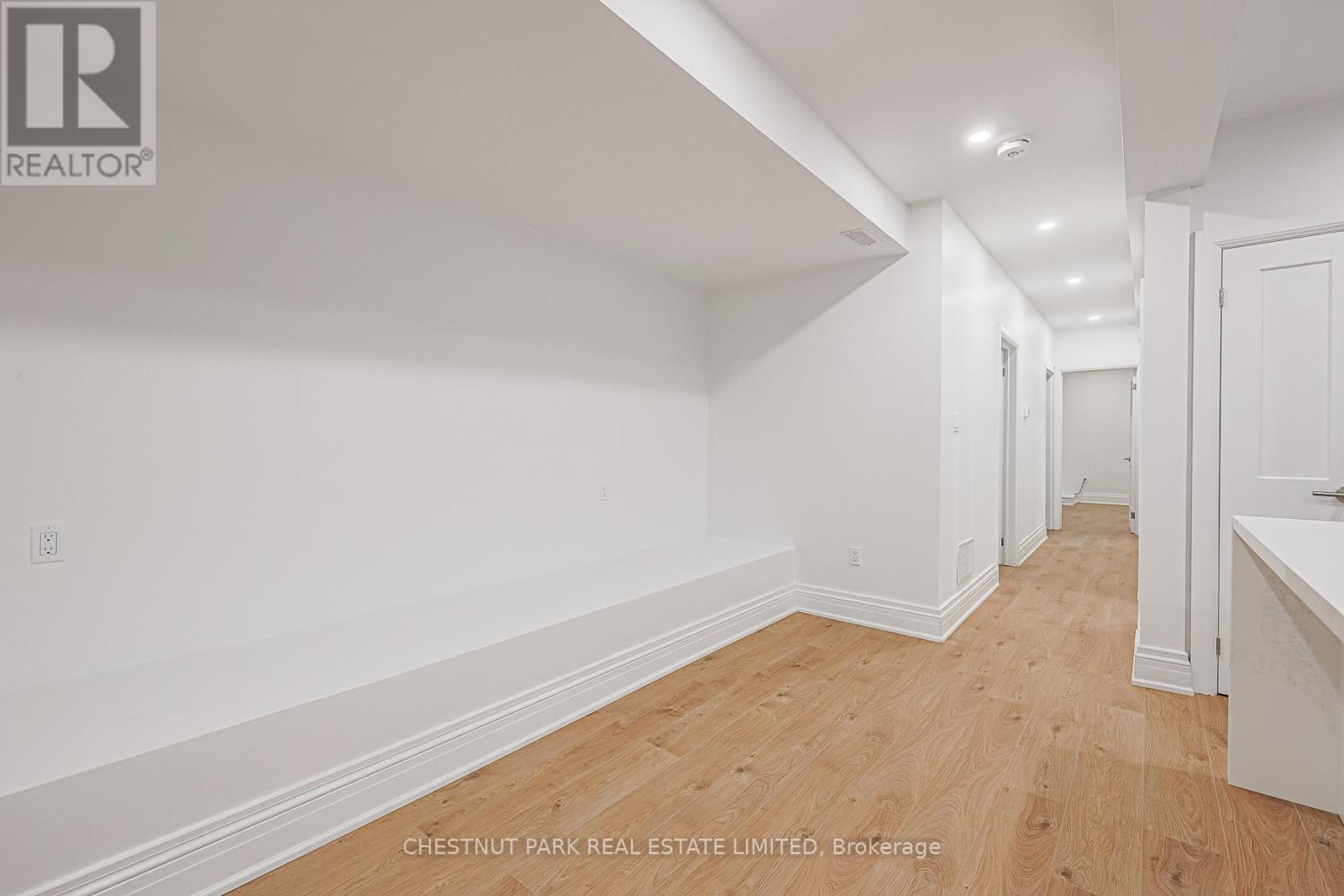 A long hallway with wood floors and white walls.