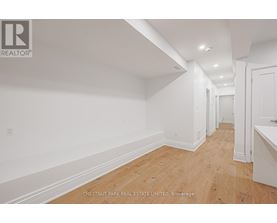 A long hallway with wood floors and white walls.