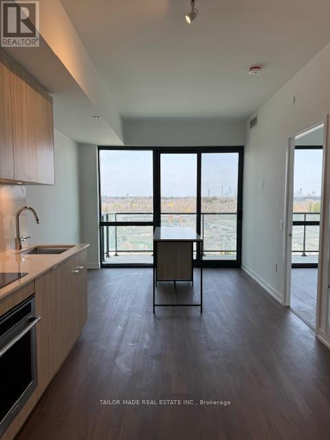 A modern kitchen with wooden cabinets and a large window overlooking a field.