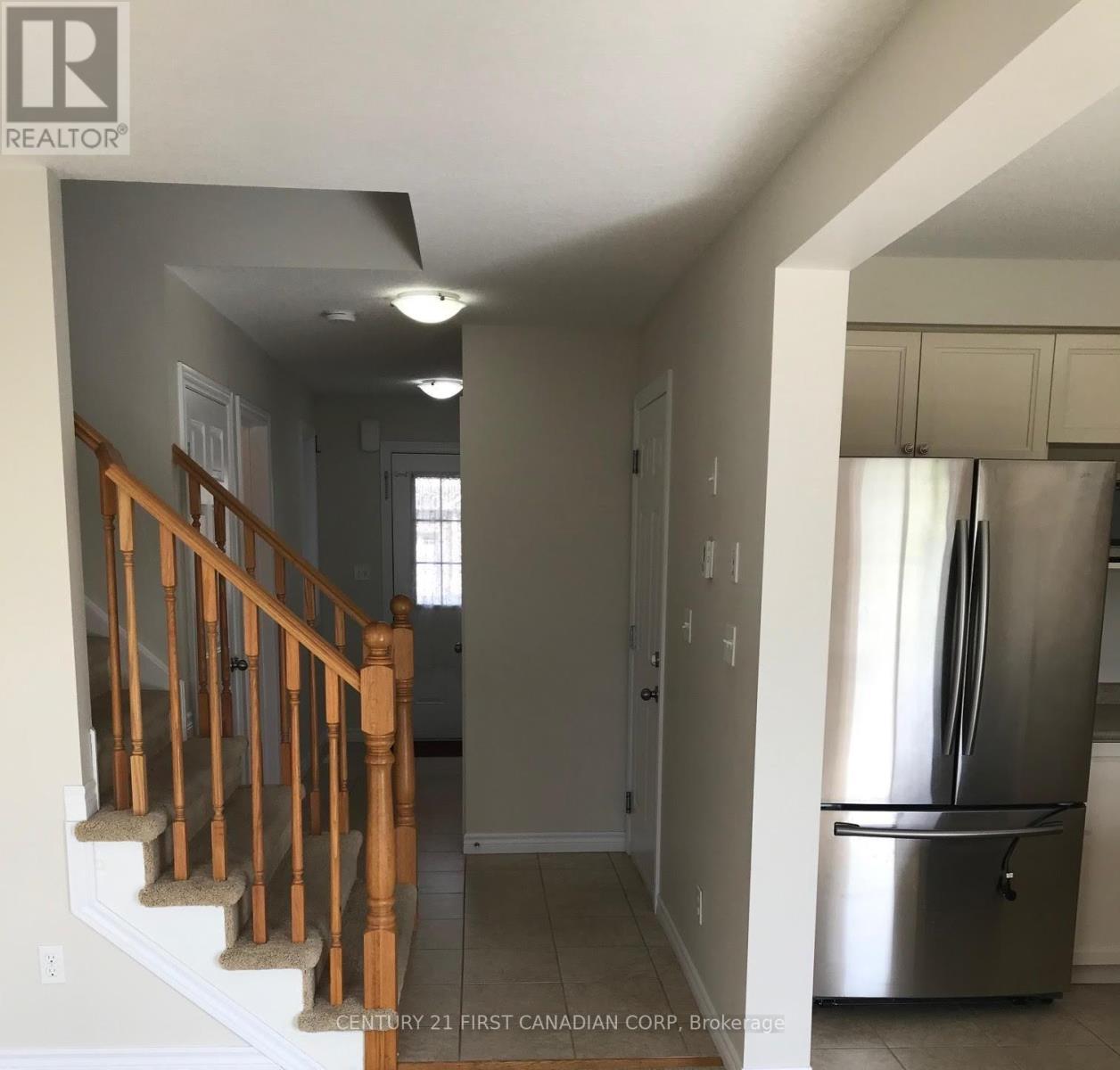 A kitchen with a stainless steel refrigerator and wooden stairs.