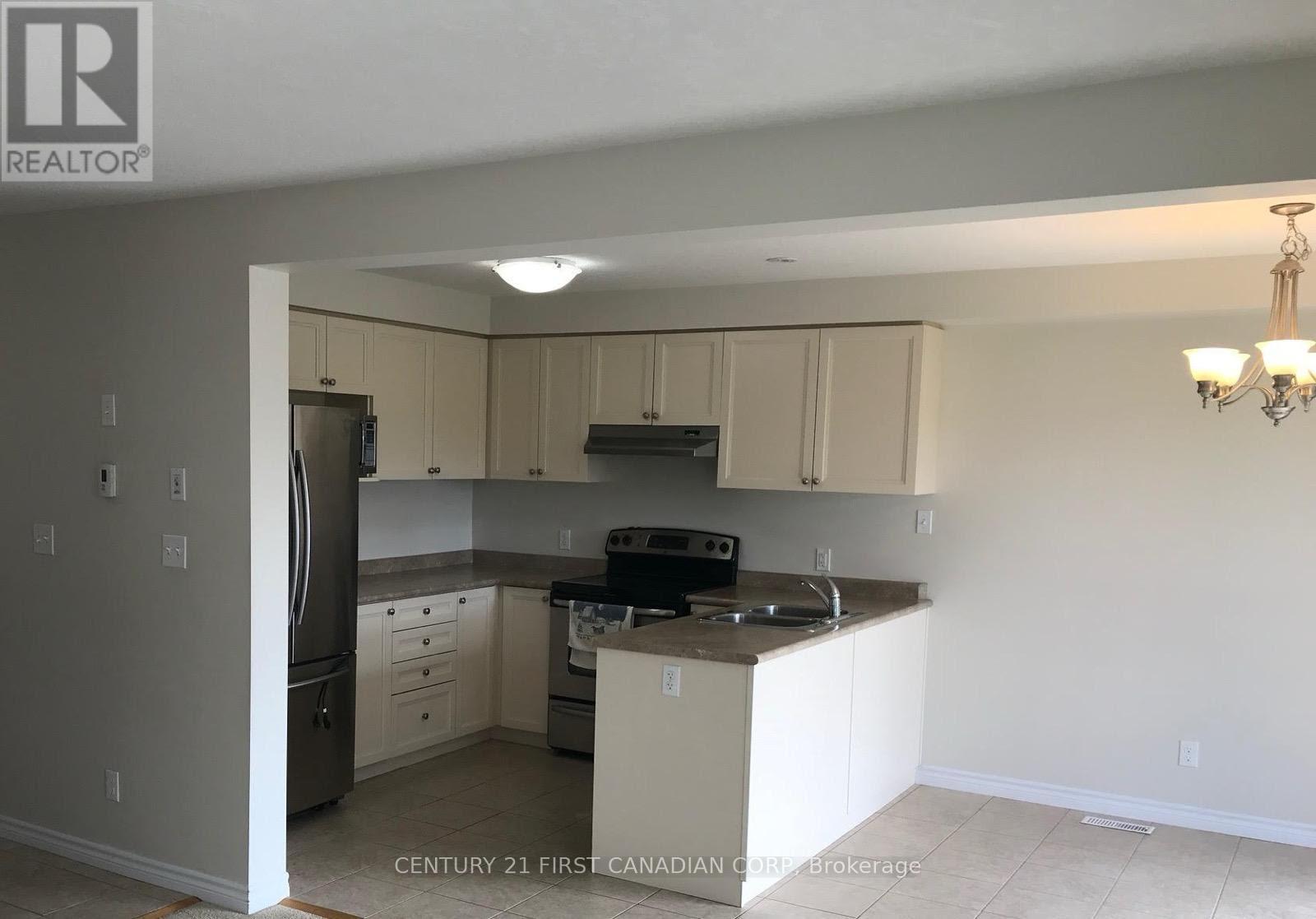 A kitchen with a refrigerator, sink, and cabinets.