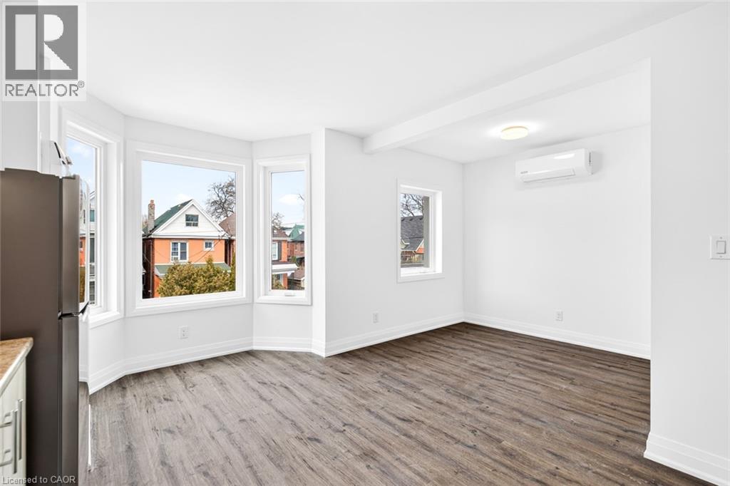 A spacious room with wood flooring and white walls.