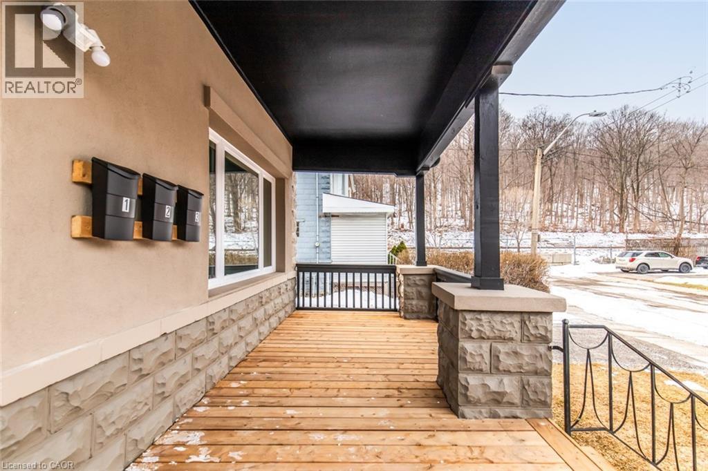 A wooden deck with a black railing and a stone pillar.