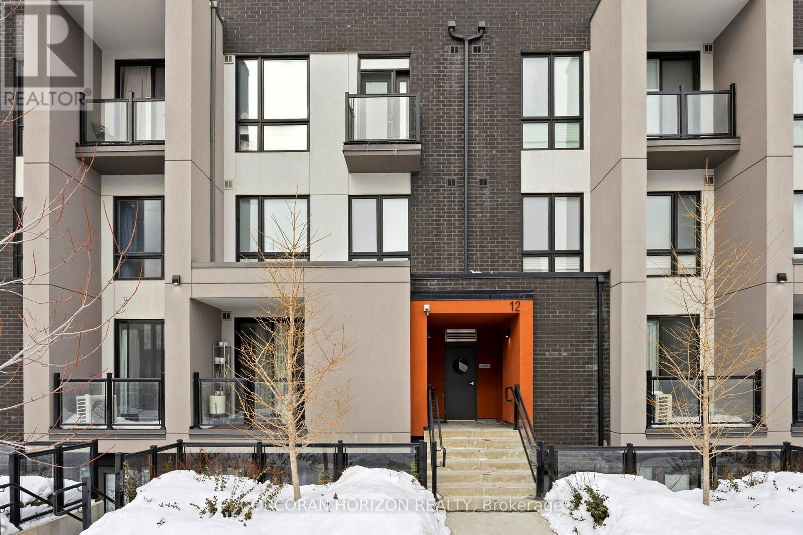 A modern apartment building with a red door and stairs leading up to it.