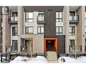 A modern apartment building with a red door and stairs leading up to it.