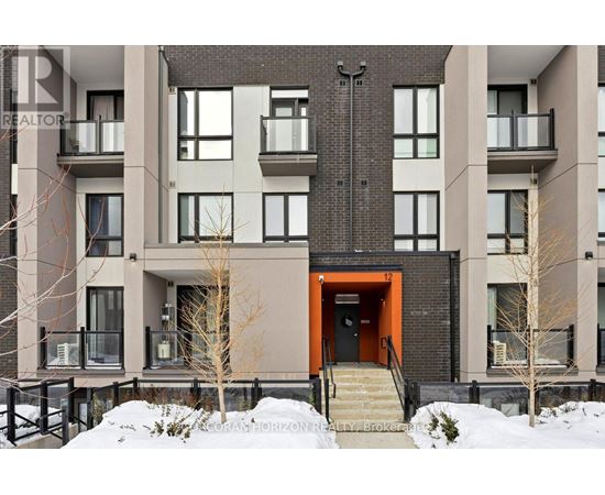 A modern apartment building with a red door and stairs leading up to it.