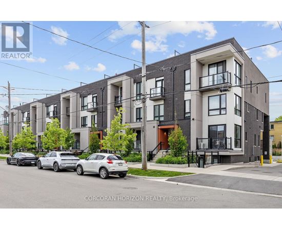A row of modern townhouses with cars parked in front.