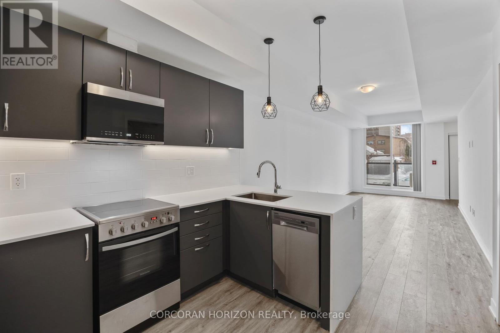 A modern kitchen with dark brown cabinets and stainless steel appliances.