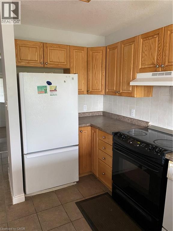 A kitchen with a white fridge and black oven.