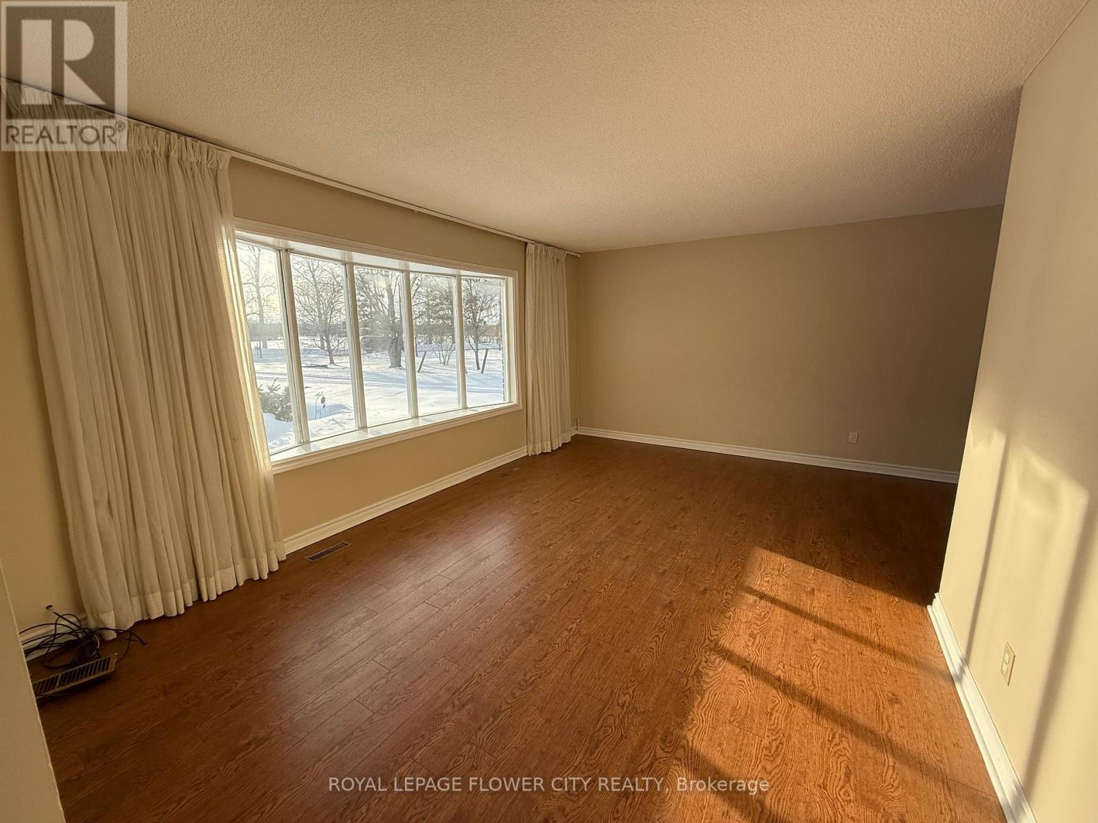 A room with wooden flooring and a window with curtains.