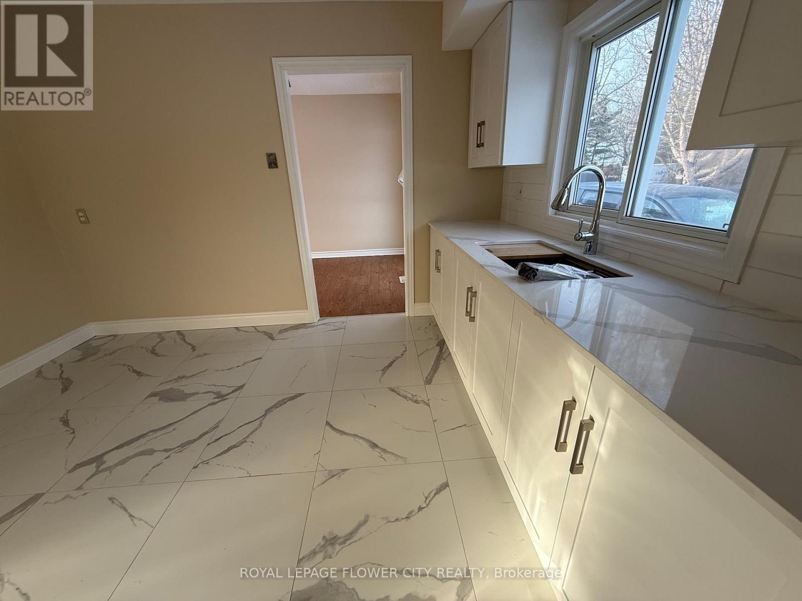 A kitchen with marble flooring and white cabinets.