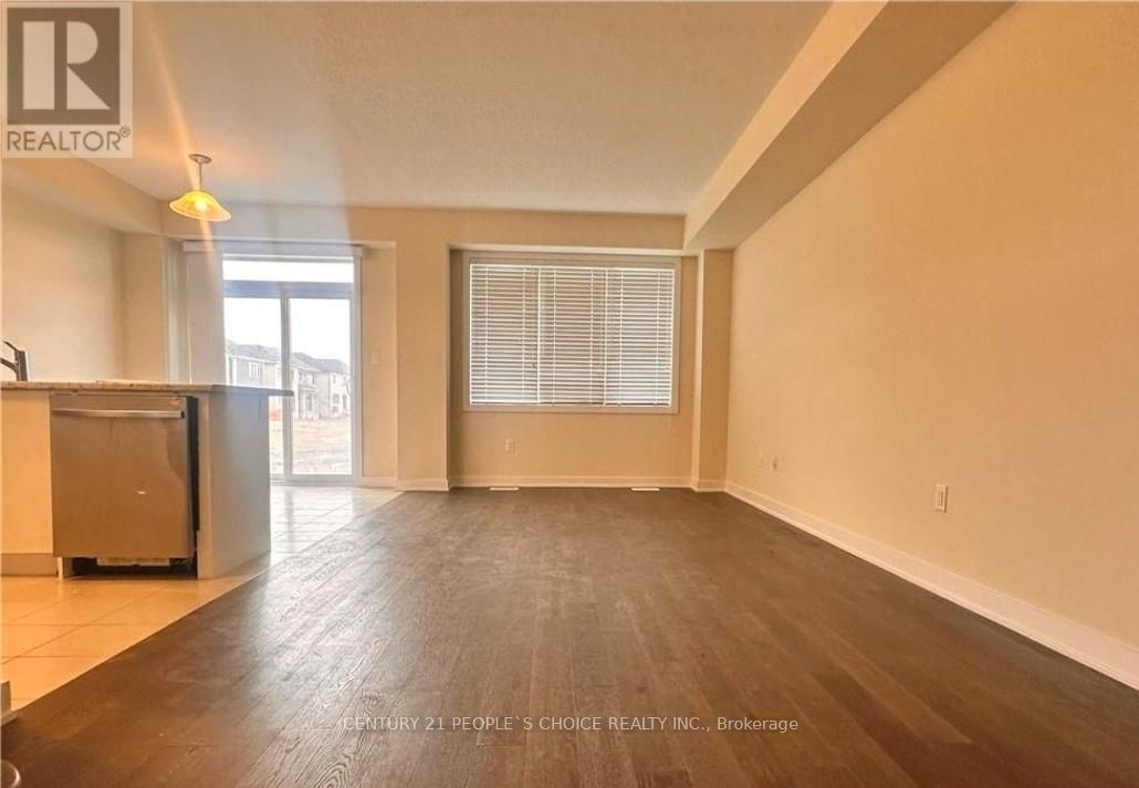 A spacious room with wooden flooring and a large window with blinds.
