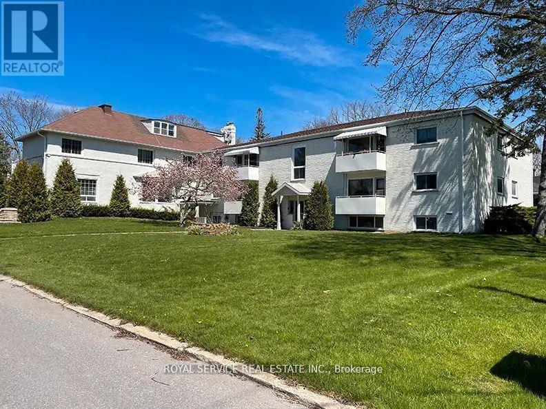 A white building with a red roof is surrounded by a green lawn.