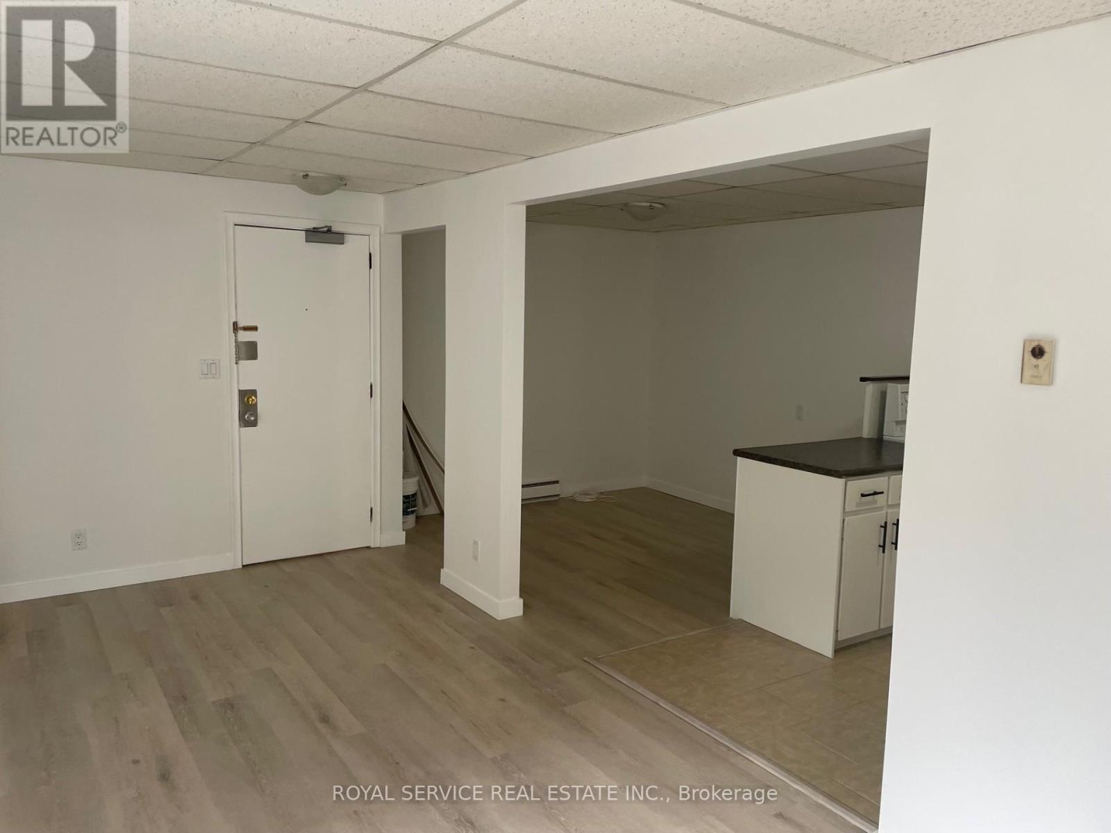 A white room with a door and a kitchenette.