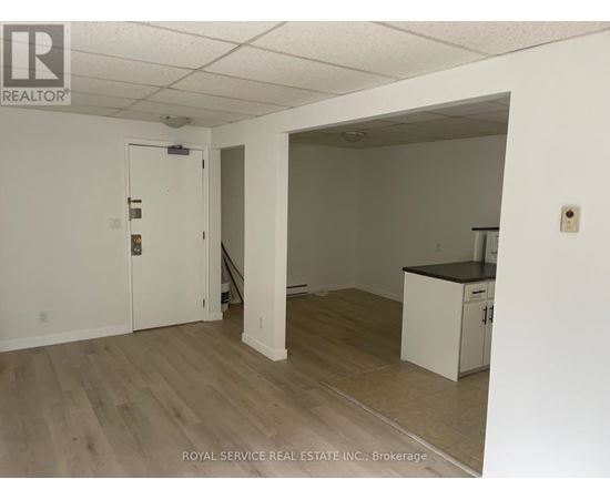 A white room with a door and a kitchenette.