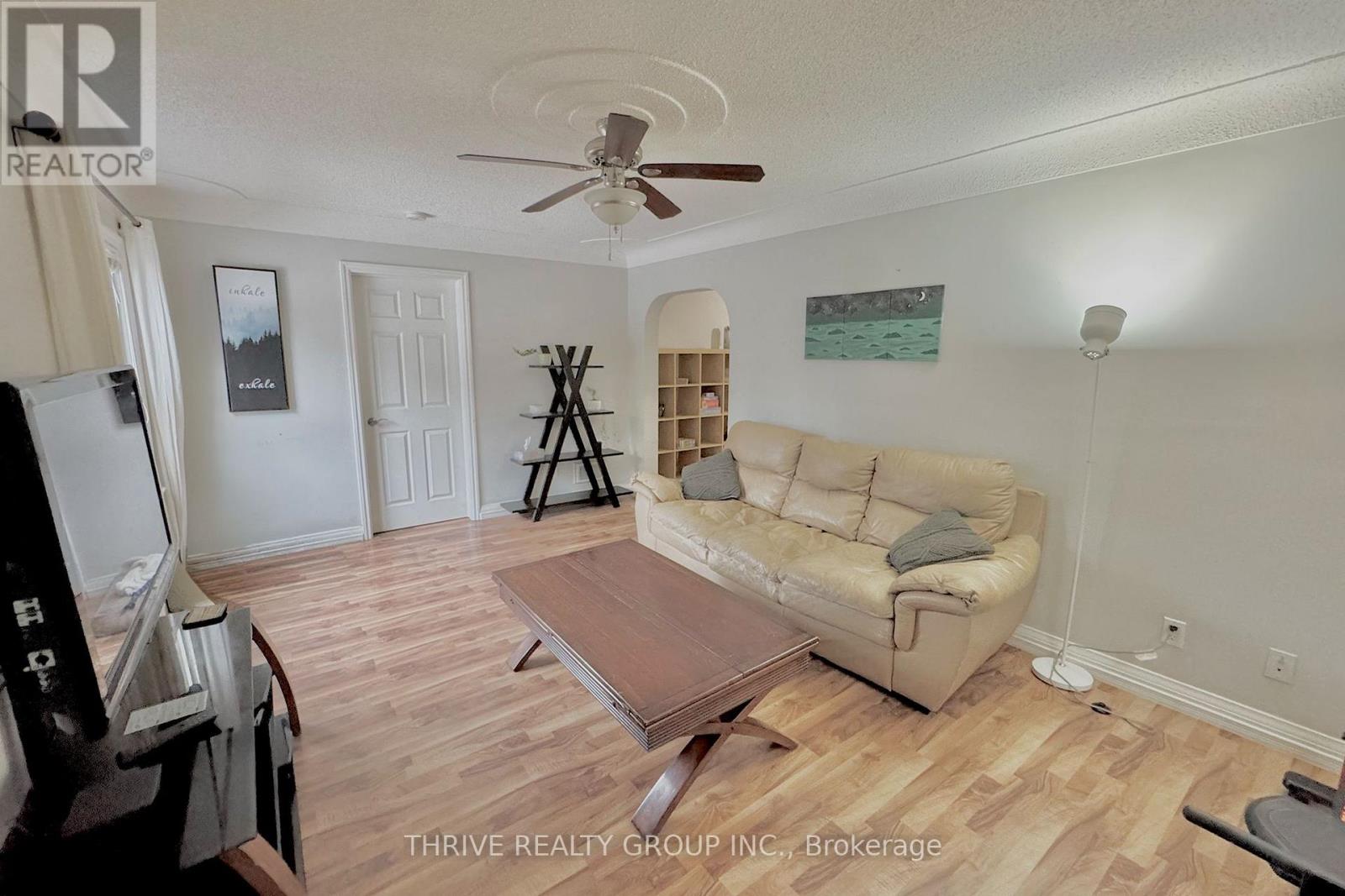 A living room with a couch, a coffee table, and a ceiling fan.