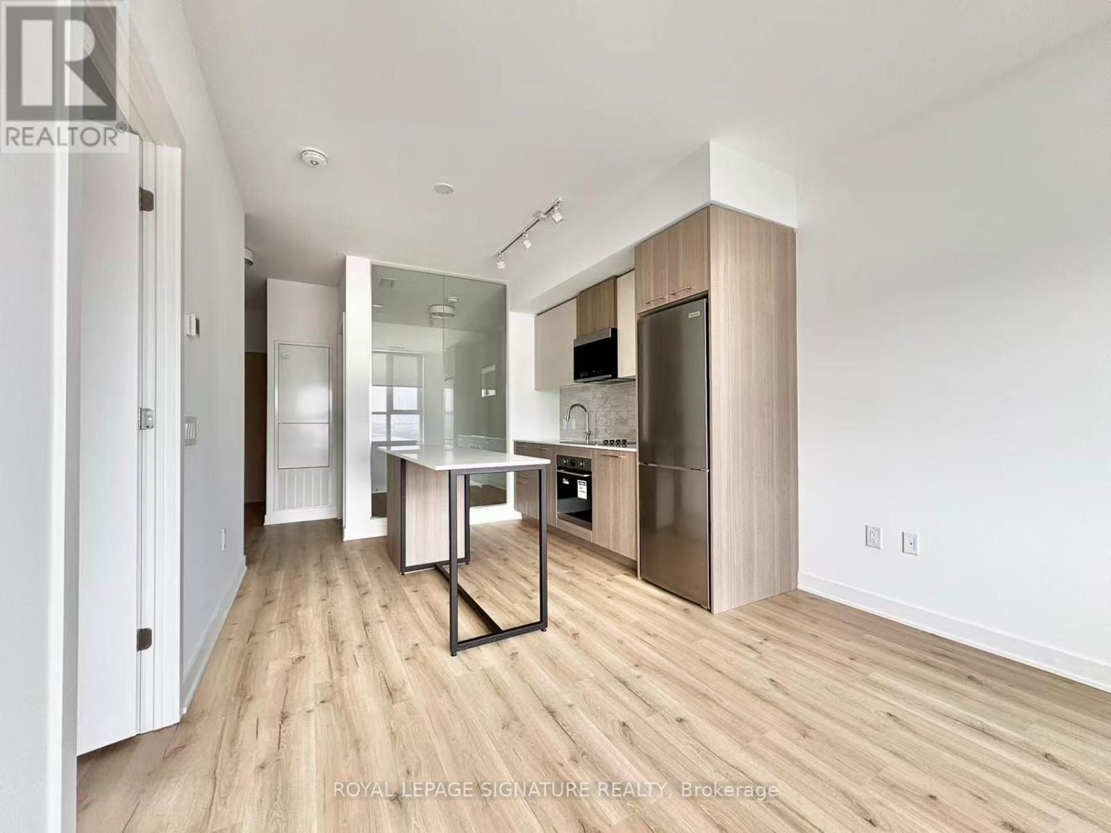 A modern kitchen with wooden floors and white walls.