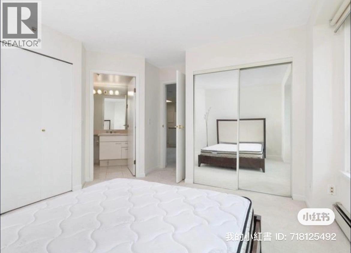 A bedroom with a large bed and a mirrored closet door.