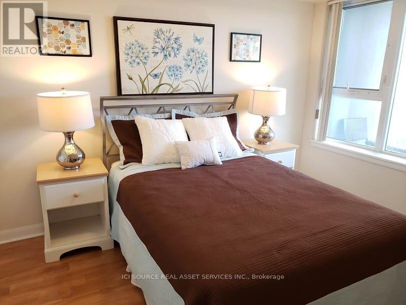 A bedroom with a bed, nightstands, and pictures on the wall.