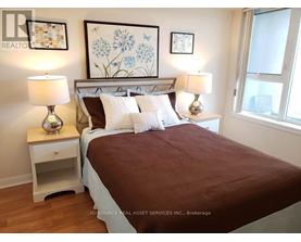 A bedroom with a bed, nightstands, and pictures on the wall.