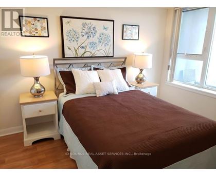 A bedroom with a bed, nightstands, and pictures on the wall.