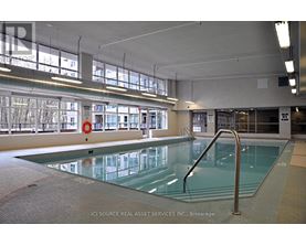 A large indoor swimming pool with a glass bottom and a metal ladder on the right side.