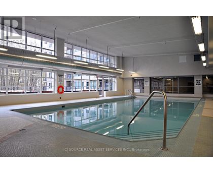 A large indoor swimming pool with a glass bottom and a metal ladder on the right side.