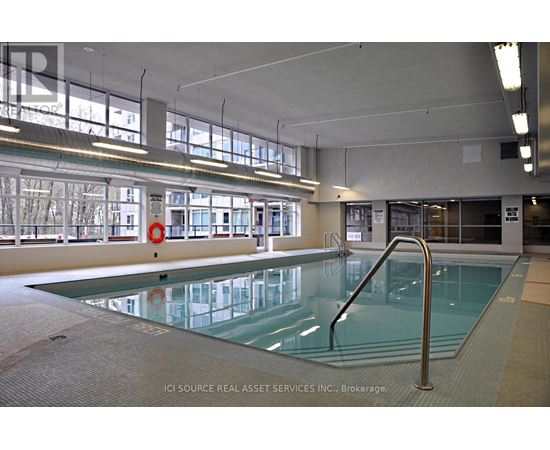 A large indoor swimming pool with a glass bottom and a metal ladder on the right side.