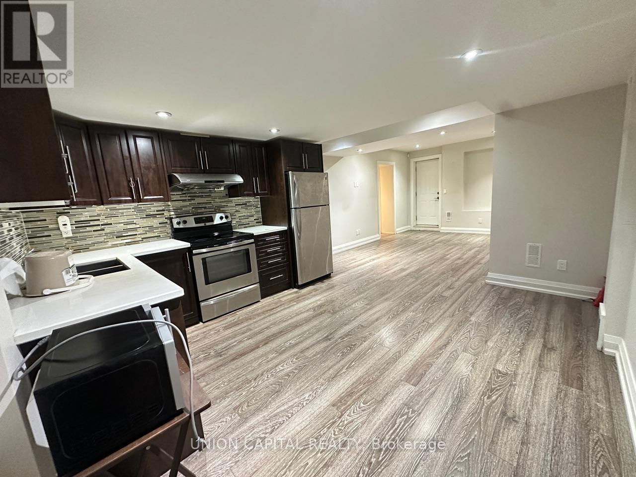 A kitchen with wooden cabinets and a stone backsplash.