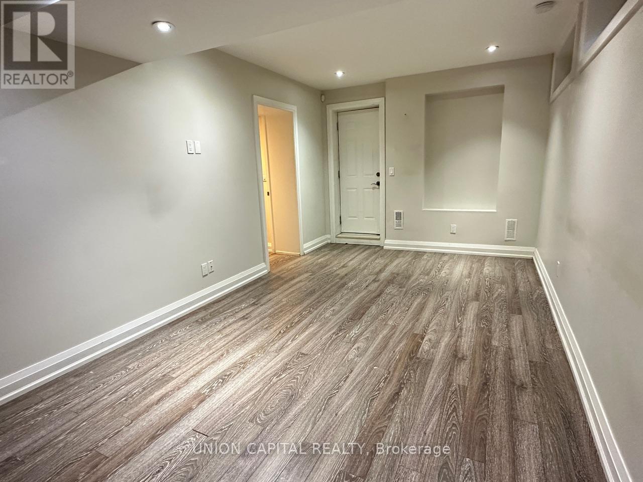 A spacious room with wood flooring and two doors.