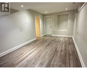 A spacious room with wood flooring and two doors.
