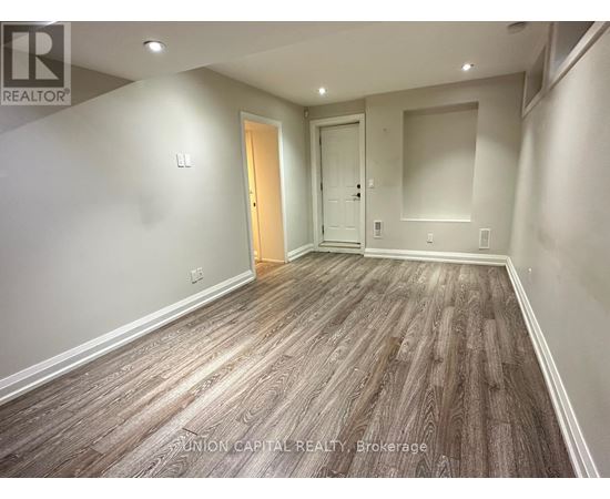 A spacious room with wood flooring and two doors.