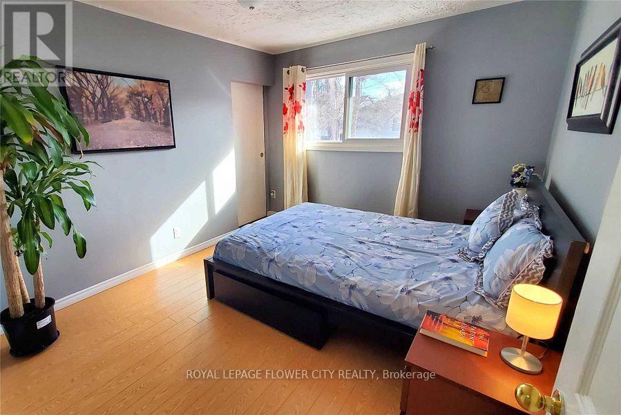 A bedroom with a bed, nightstand, and a plant.