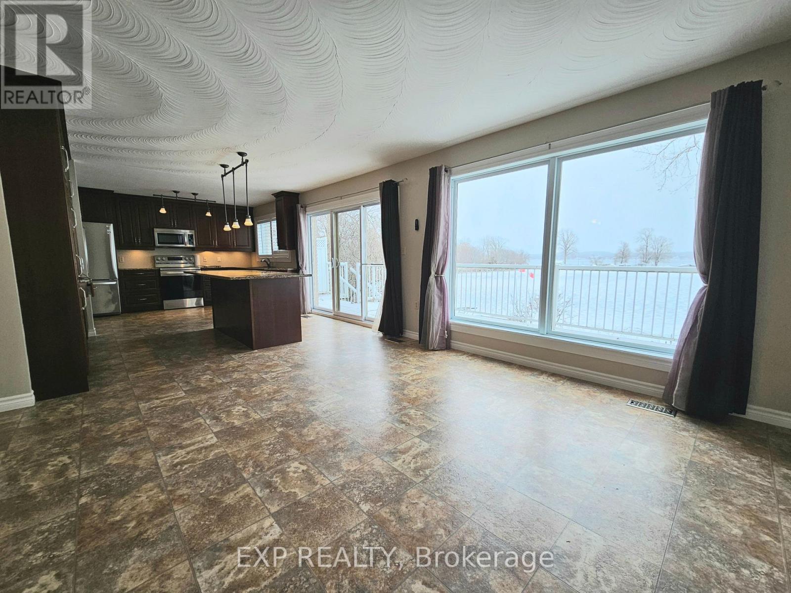 A spacious room with a large window and a view of a fence.